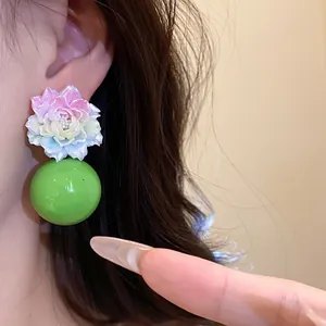 Close-up of vibrant multi-colored resin flower earring with large glossy green ball drop.
