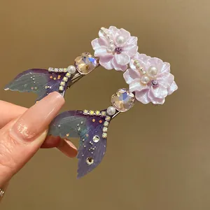 Close-up of mermaid tail hair clips with pink flowers, pearls and shiny rhinestones