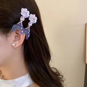 Close-up view of elegant purple flower and mermaid tail hair clips worn on long dark hair