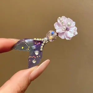 Macro detail of elegant mermaid tail hair clip decorated with pink flower and pearls