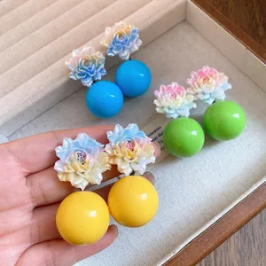 Macro view of colorful resin flower and round bead drop earrings displayed in a jewelry box