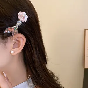 Close-up detail of a sweet mermaid tail and pink flower hair clip worn by a model