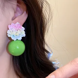 Close-up of vibrant multi-colored resin flower earring with large green sphere bead