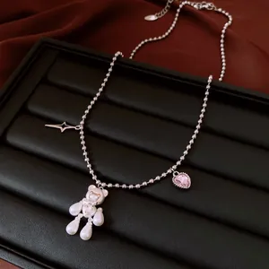 Macro view of silver bead necklace featuring pearl bear and pink heart zircon charms