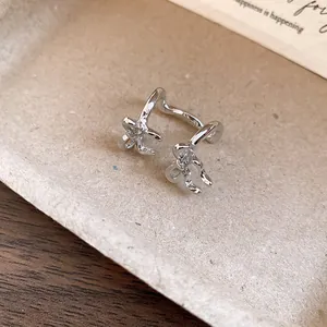 Close-up detail of silver double-layered bow ear cuff jewelry with a minimalist design.