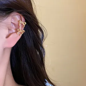 Detailed macro view of elegant golden bow-shaped ear cuffs worn on a model's ear