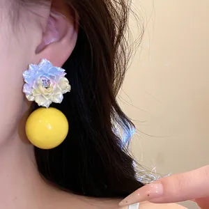Sweet resin flower stud earrings with a large yellow bead design shown on a model