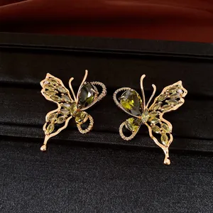 Detailed macro view of 18K gold plated butterfly earrings featuring green zircon stones