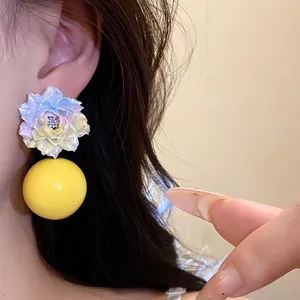 Close-up detail of a pastel resin floral earring with a smooth yellow spherical drop.