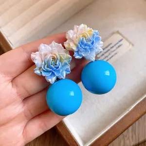 Detailed view of sweet resin floral earrings featuring large bright blue spherical drops