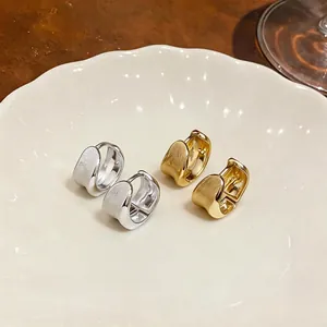 Minimalist 18K gold and silver plated brushed hoop earrings presented on a white plate