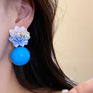 Close-up detail of sweet blue resin flower earrings with a large spherical bead on an ear