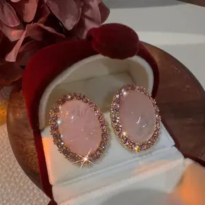 Primo piano di orecchini ovali rosa in stile vintage in una scatola di velluto rosso