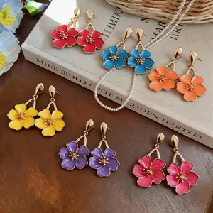 Vibrant multi-colored oil-drop flower earrings elegantly arranged on a vintage book.