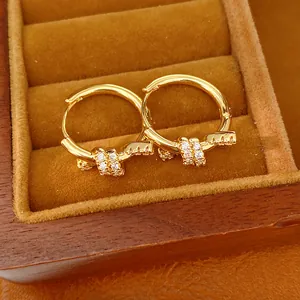 Close-up of 14k gold plated knotted hoop earrings with sparkling zircon stones in a box