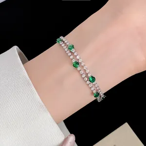 Κοντινό πλάνο 18k επιχρυσωμένο βραχιόλι με διπλή σειρά ζιργκόν και πράσινες πέτρες