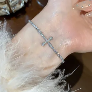 Close-up detail of silver-toned 18k gold plated cross bracelet with sparkling zircons.