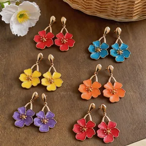 Multiple pairs of colorful oil-drop flower earrings displayed on a wooden surface