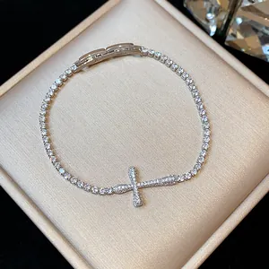 High-quality close-up of an 18k gold plated zircon cross bracelet on a luxury box
