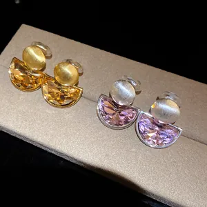 Detailed close-up view of vintage semi-circular crystal ear clips in gold and silver tones.