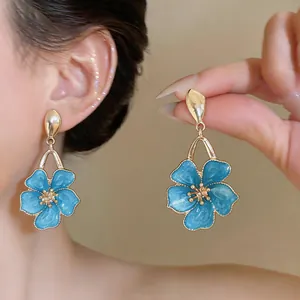 Detailed view of elegant blue enamel flower drop earrings with golden metal trim