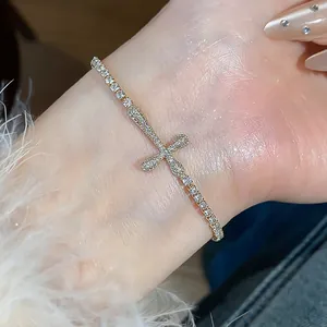 Detailed view of a sparkling 18k gold plated cross bracelet pavé-set with zircons on wrist