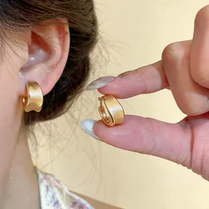 Close-up of 18K gold plated brushed hoop earrings showing texture and fit
