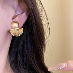 Close-up detail of vintage gold-toned semi-circle clip-on earrings with yellow crystal