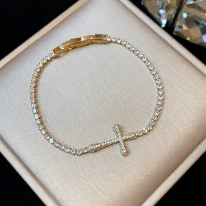 Macro view of an 18k gold plated tennis bracelet with a sparkling zircon cross