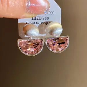 Close-up of pink semi-circular crystal earrings with silver brushed studs
