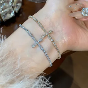 Close-up of elegant gold and silver cross bracelets with sparkling zircons on wrist
