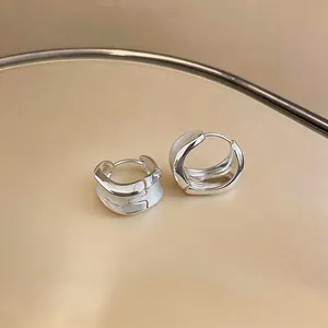 Detailed macro view of minimalist silver hoop earrings with a textured brushed metal finish