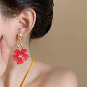 Close-up detail of elegant red enamel flower drop earrings on model for summer vacations