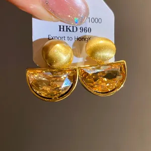 Detailed macro view of vintage gold stud earrings with semi-circular crystal pendants