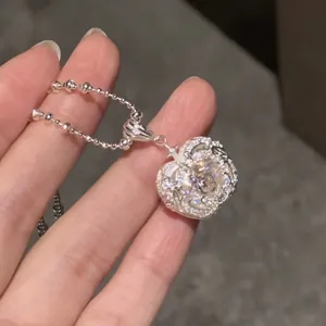 Detailed macro view of a silver heart-shaped zircon pendant necklace on a ball chain.