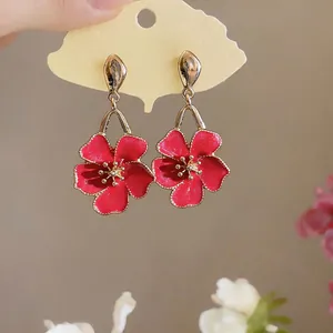 Detailed close-up view of vibrant red enamel flower dangle earrings on ginkgo leaf card