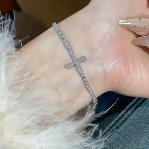 Close-up detail showing a shiny 18k gold plated zircon cross bracelet on a wrist