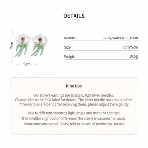 Spécifications détaillées pour boucles d'oreilles fleur en résine, hirondelle et strass.
