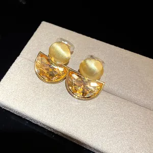 Macro detail of vintage amber crystal semi-circle earrings on a gray display pad