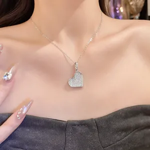 Close-up view of a heart-shaped pendant necklace featuring pave-set zircon stones on a model