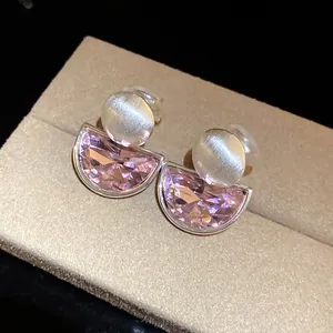 Close-up of semi-circular pink crystal ear clips with brushed metallic round detail