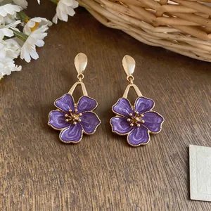 Detail view of sweet purple enamel flower earrings with intricate golden swirls.