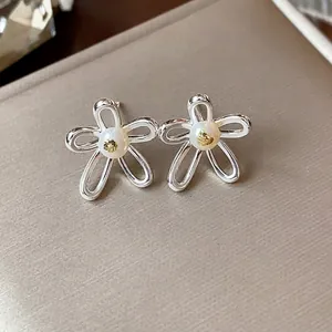 Elegant silver hollow flower stud earrings with a pearl center and gold leaf accent