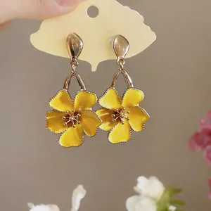 Macro detail shot of yellow enamel flower drop earrings with elegant golden finish.
