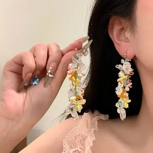Detailed view of handmade multi-color floral beaded tassel earrings on model's ear