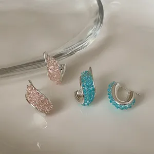 Primo piano di orecchini d'argento intrecciati con cristalli rosa e blu incastonati