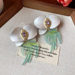 Vue macro détaillée d'élégantes boucles d'oreilles fleurs en résine avec cristaux violets.
