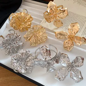 Detailed view of gold and silver pleated metal flower cuff bracelets on a tray