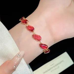 Elegant gold-plated bracelet with vibrant teardrop red zircon stones on a model's wrist