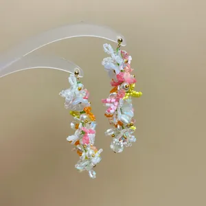 Detailed macro view of handmade colorful floral beaded tassel earrings with pearls.